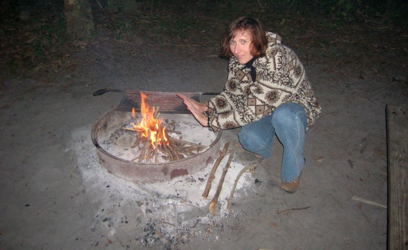 Milena is warming up at campfire.