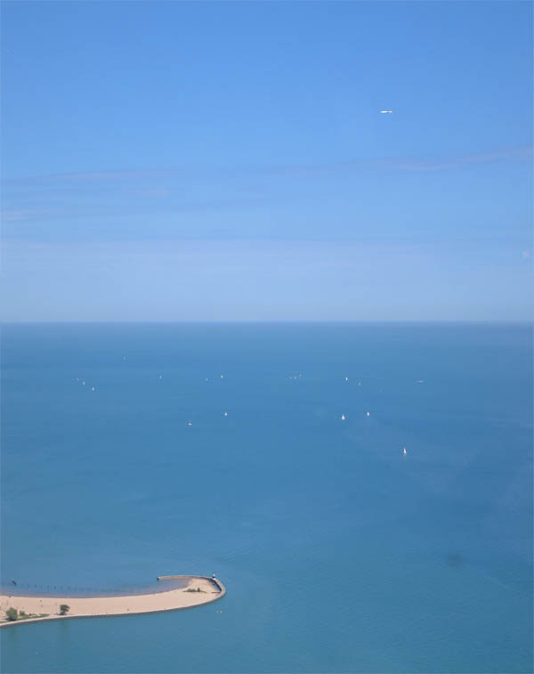 Yachts on the azure-blue lake and an airplane above it