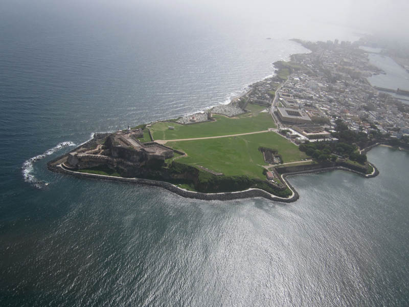 Fort El Morro, green field of fire, and the old town at right